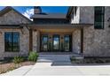 A front entrance with gray trim, dark windows, and a stone exterior with a front porch and concrete entryway at 2442 Fox View Trl, Franktown, CO 80116