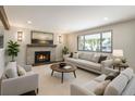 Cozy living room with a brick fireplace, neutral furniture, and a large picture window at 6330 E Vassar Ave, Denver, CO 80222