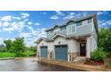 Beautiful townhome featuring two-car garage, stone accents, and manicured landscaping on a wet day at 1106 Oak Cir, Lakewood, CO 80215