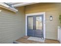Close-up of the front door with glass panels, wooden deck, and exterior lighting at 314 Woodstock Ln, Castle Pines, CO 80108