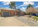Inviting brick home with a covered front porch, well-manicured lawn, and blooming tree at 882 E Briarwood Cir, Centennial, CO 80122