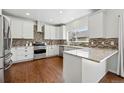 Modern kitchen featuring white cabinets, stainless steel appliances, granite counters, and tile backsplash at 7430 E Bayaud Ave, Denver, CO 80230