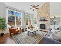 Bright living room featuring a fireplace with stone accents, hardwood floors, and large windows at 7430 E Bayaud Ave, Denver, CO 80230