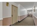 A carpeted hallway showing the entrance to the apartment, highlighted by a vintage light fixture at 13606 E Bates Ave # 304, Aurora, CO 80014