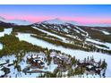 Expansive aerial shot captures a luxurious log home near a ski resort with ski slopes and snow-covered mountains at 422 Timber Trail Rd, Breckenridge, CO 80424