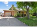 Brick house with a detached garage and mature trees, showing the driveway at 6050 Marshall Ct, Arvada, CO 80003