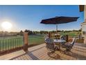 Relaxing deck with outdoor seating, a table, and an umbrella overlooking a green landscape at 17635 Silver Fox Ct, Mead, CO 80542