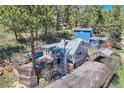 Aerial view of the gray home with a deck, outdoor seating, lush greenery, and parking area at 27389 Highway 74, Evergreen, CO 80439