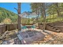 Inviting outdoor patio area with a table, chairs, umbrella, and wooden terraced landscaping at 27389 Highway 74, Evergreen, CO 80439