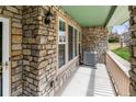 Covered porch featuring stone columns, an AC unit and windows at 619 S Norfolk Way, Aurora, CO 80017