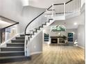 Bright, open living space with wood floors, a winding staircase, and fireplace, perfect for gathering and relaxation at 7873 Sweet Water Rd, Lone Tree, CO 80124