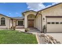 Inviting front entrance with a beautiful wooden door, complemented by well-maintained landscaping and an arched entry at 1720 Chaparro Cir, Berthoud, CO 80513