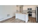 Modern kitchen featuring an island, stainless steel appliances, and hardwood flooring at 15277 Fillmore St, Thornton, CO 80602