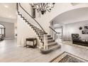 Inviting foyer featuring a grand staircase with elegant chandelier and wood-look flooring at 5426 S Jasper Way, Centennial, CO 80015
