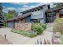 Two-story home featuring lush landscaping, a stone accent wall, and a two car garage at 7715 S Hudson Ct, Centennial, CO 80122