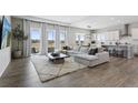 Open-concept living room with natural light, hardwood floors, and a large sectional sofa at 21894 E Tufts Cir, Aurora, CO 80015