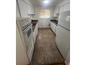 Galley kitchen featuring white cabinets, appliances, and tile floors at 1533 S Jamaica St, Aurora, CO 80012