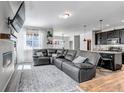 Open concept living room features sleek gray leather furniture and leads into the kitchen at 3953 John Ave, Castle Rock, CO 80104