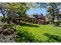 Lush green backyard with patio, pergola, garden area, and mature landscaping at 1193 Phipps Ct, Highlands Ranch, CO 80126