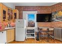 Compact kitchen featuring brick walls, light wood cabinets, and stainless appliances at 1450 N High St # 3, Denver, CO 80218