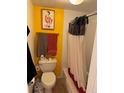 Bathroom with yellow accent wall with framed art, neutral colored shower curtain and towels at 1888 S Jackson St # 404, Denver, CO 80210