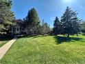 A well-manicured green lawn leads to homes partially obscured by mature trees on a bright day at 11576 E Bayaud Dr, Aurora, CO 80012