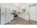 The kitchen features stainless steel appliances, white cabinets and wood flooring at 12063 E Arizona Dr, Aurora, CO 80012