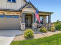 Inviting front porch with rocking chairs, stone pillars, and a well-manicured lawn at 7702 E 157Th Ave, Thornton, CO 80602