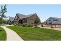 Well-maintained front yard with lush green grass, mature landscaping, and a sidewalk at 7702 E 157Th Ave, Thornton, CO 80602