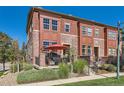 Charming townhome with a red brick facade, front porch, and manicured landscaping under a bright blue sky at 535 Elmhurst Way # A, Highlands Ranch, CO 80129