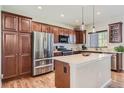 Modern kitchen featuring stainless steel appliances, an island, and rich wood cabinetry with hardwood floors at 535 Elmhurst Way # A, Highlands Ranch, CO 80129