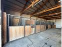 View of the barn interior featuring horse stalls with metal bars and wooden partitions at 32350 E 137Th Way, Brighton, CO 80603