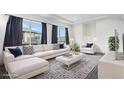 Bright living room with modern furnishings, plush white sofas, and large windows with elegant curtains at 19096 E 55Th Ave, Denver, CO 80249