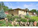Rear view of a well-maintained brick home, complemented by lush greenery and mature trees at 5703 Field St, Arvada, CO 80002
