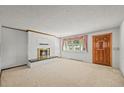 Cozy living room features a brick fireplace, neutral carpet, and a window with pink accents at 5703 Field St, Arvada, CO 80002