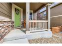 Charming front porch featuring a bright green door, stone accents, and a cozy seating area at 30 Sun Up Ct, Erie, CO 80516