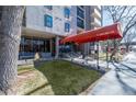 Building entrance featuring a red awning at 2 Adams St, landscaping, and seating area at 2 Adams St # 905, Denver, CO 80206