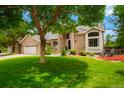 Beautiful home with mature trees, a well-manicured lawn, and a charming brick exterior at 2061 Chesapeake Pl, Highlands Ranch, CO 80126