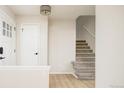 Inviting entryway with hardwood floors, white trim, modern lighting and access to the carpeted staircase at 4760 S Wright Way, Morrison, CO 80465