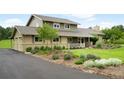 Well-maintained two-story home with landscaped flowerbeds, a paved driveway, and mature trees at 5586 Colorow Dr, Morrison, CO 80465