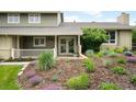 Inviting covered front porch with double doors, framed by lush landscaping with vibrant purple flowers at 5586 Colorow Dr, Morrison, CO 80465