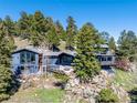Unique architectural home nestled atop a rocky cliffside surrounded by lush, mature trees at 22598 Westview Ave, Golden, CO 80401