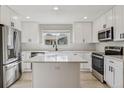 Bright kitchen featuring stainless steel appliances, white cabinets, quartz countertop island and tile backsplash at 46 Douglas Dr, Broomfield, CO 80020