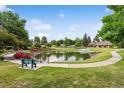 Picturesque community pond with a walking path, fountain, bench, and landscaping at 46 Douglas Dr, Broomfield, CO 80020
