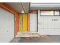 Close-up of the front entrance featuring a bright yellow door and white brickwork, adjacent to a garage at 5405 S Lowell Blvd, Littleton, CO 80123