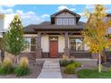 Charming single-Gathering home featuring a covered front porch, stone accents, and a well-maintained front yard with grass and bushes at 20968 E 60Th Pl, Aurora, CO 80019