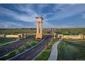 Scenic view of the community entrance with a clock tower, manicured landscaping, and welcoming signage at 23991 E 40Th Ave, Aurora, CO 80019