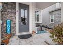 Inviting front porch with stone veneer, gray door, and seating area at 17217 E Exposition Dr, Aurora, CO 80017