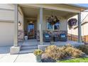 Inviting front porch with comfortable seating and colorful hanging flower baskets at 697 Gamble Oak St, Brighton, CO 80601