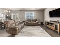 Comfortable living room featuring plush reclining sofas, a large window, and hardwood floors at 697 Gamble Oak St, Brighton, CO 80601
